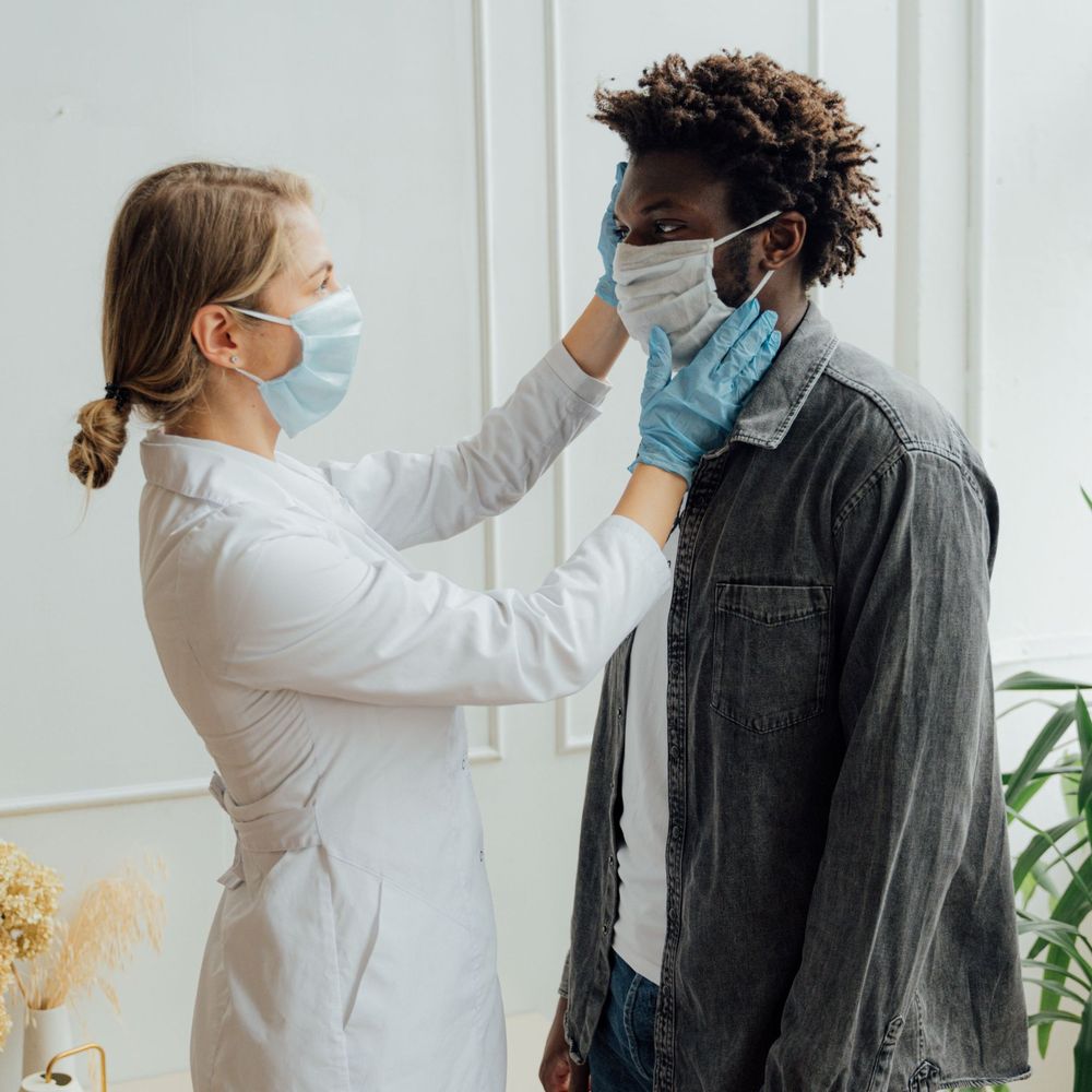 A nurse in gloves and a face mask gently checking a patient